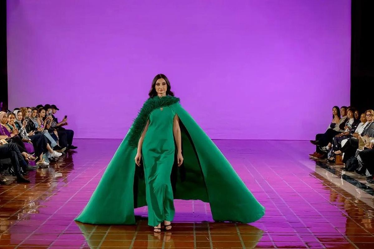 A model in an emerald cape gown walks the runway at New York Fashion Week with The Bureau